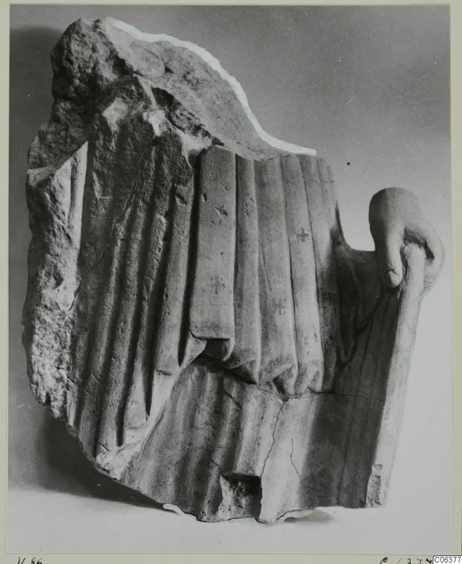 Limestone sculpture fragment from Vouni with carved vertical drapery folds and a hand at the right edge