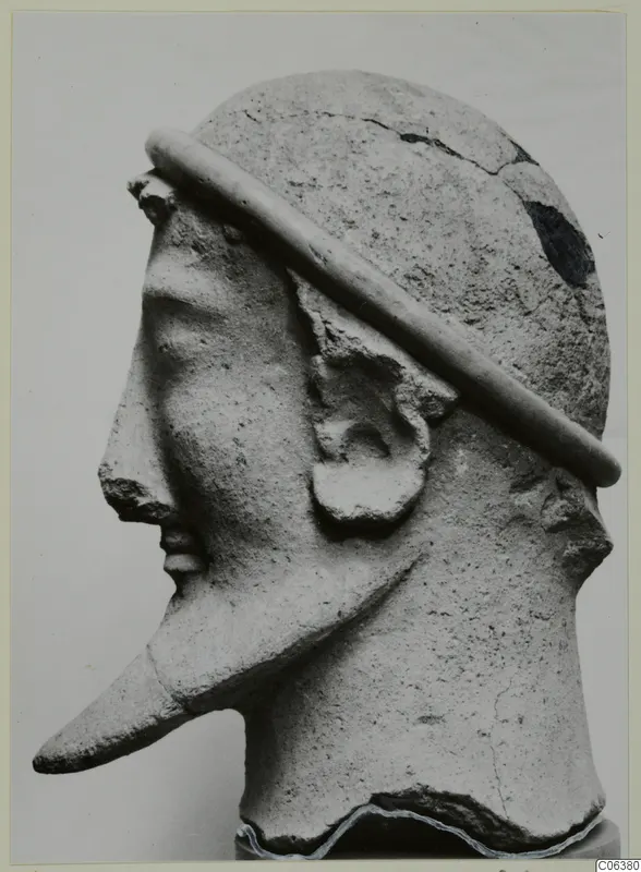 Terracotta head sculpture in profile facing left, with a band across the crown and a long pointed projection from the lower face
