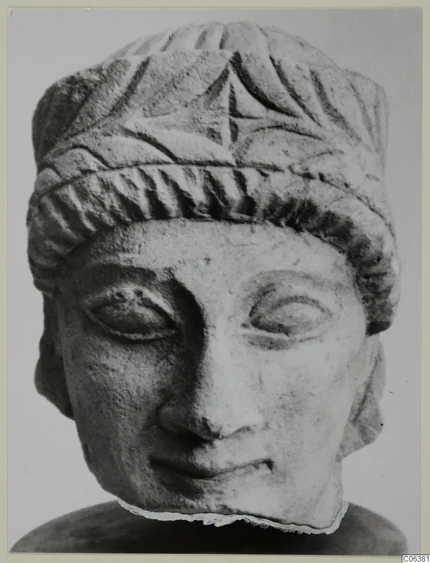 Carved limestone head from Mersinaki with a fluted headdress and a band across the brow