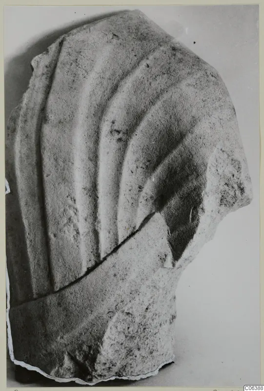 Limestone sculpture fragment from Vouni with carved curving folds, broken along its lower edge