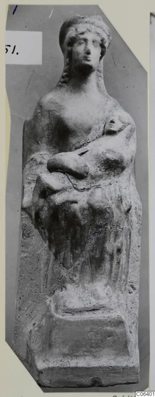 Terracotta figurine of a female figure in a tall headdress, holding a small figure or object against her chest.