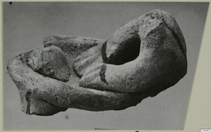 Broken terracotta fragment with an oval opening and a ridged section, shown on a grey backdrop