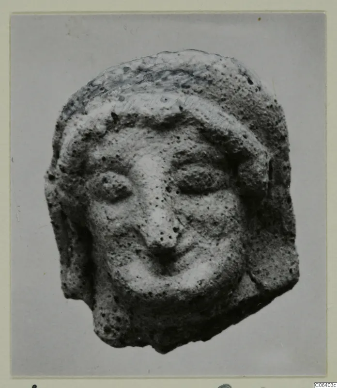 Small head of a figure in terracotta, with a headband, large eyes, a prominent nose and a wide mouth