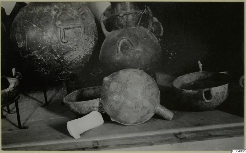 Several pottery vessels on a wooden shelf at the Cyprus Museum, including a bowl with a radiating painted pattern