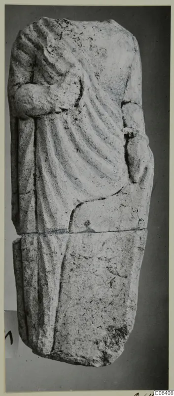Limestone statue fragment of a draped standing figure, broken at the top and across the middle, shown upright.