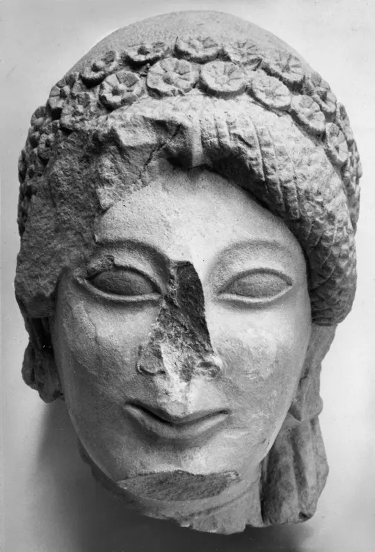 Front view of a limestone Kore statue head from Vouni, with a rosette wreath and broken nose