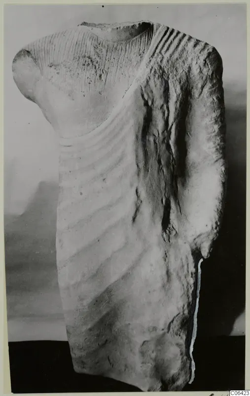 Limestone sculpture fragment from Vouni: upper torso of a figure with carved drapery folds and grooved shoulders.