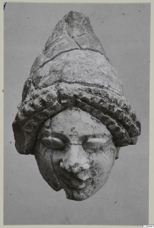 Limestone head sculpture from Vouni wearing a tall conical headdress with a ridged band, shown frontally