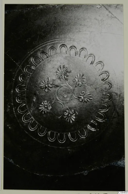 Close view of the inside of a black-glazed vessel with impressed scallop and flower decoration