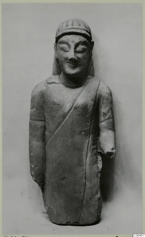 Limestone statuette of a standing figure in a long draped garment, from Kition; one forearm broken off.