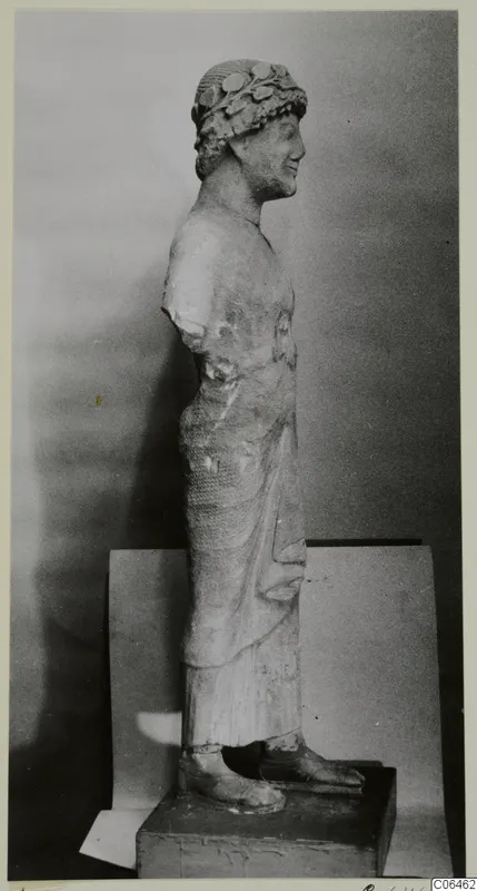Limestone sculpture from Kition of a standing figure in profile, wearing a leafy wreath, arms missing at the shoulders