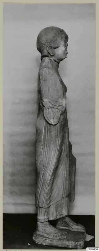 Side view of a limestone statue of a standing woman in a long pleated garment, from Vouni.