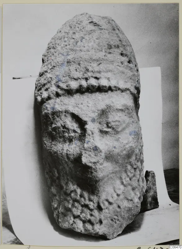 Limestone head from Kition, weathered face, standing upright on a white paper backdrop.