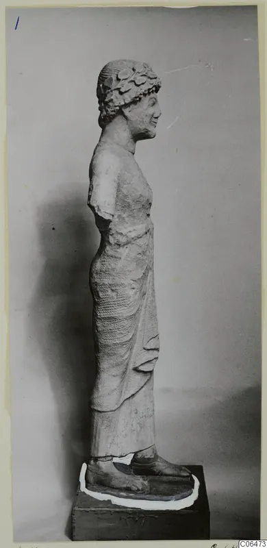 Limestone statue of a standing figure from Kition, seen in profile against a grey backdrop