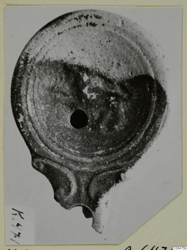 Terracotta lamp seen from above, with a central hole and a nozzle at the bottom edge
