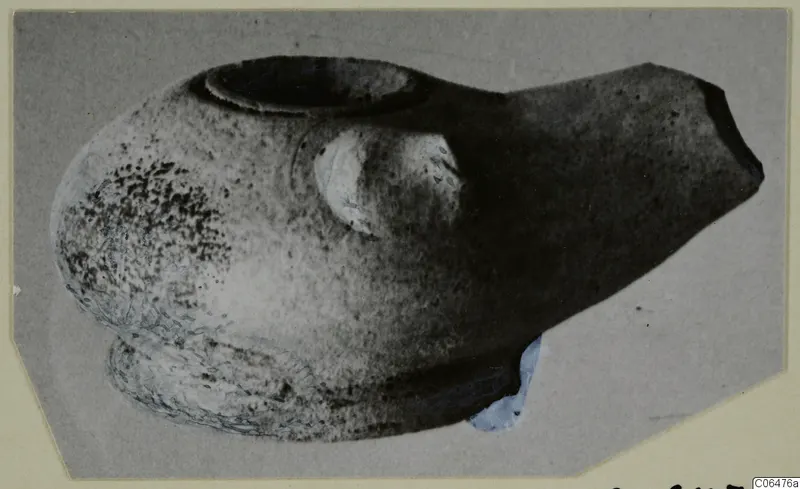 Terracotta lamp with a round filling hole and a pointed spout, shown on a grey mount
