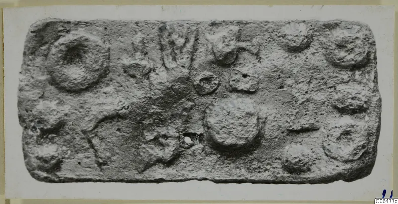 Rectangular lead plaque with raised round impressions and a small hole near the lower centre