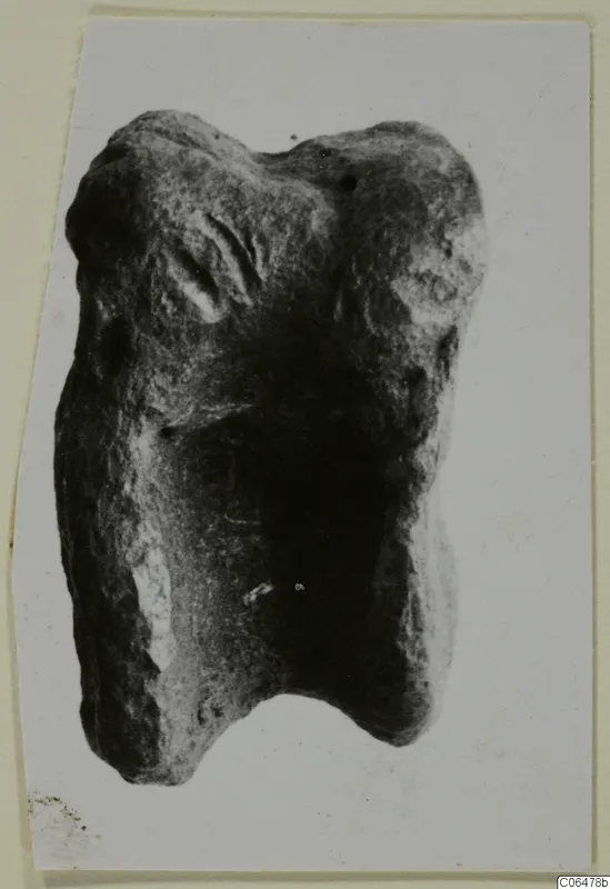 Lead fragment from Kition: a lumpy grey object with a notch in its lower edge, photographed on a card mount.