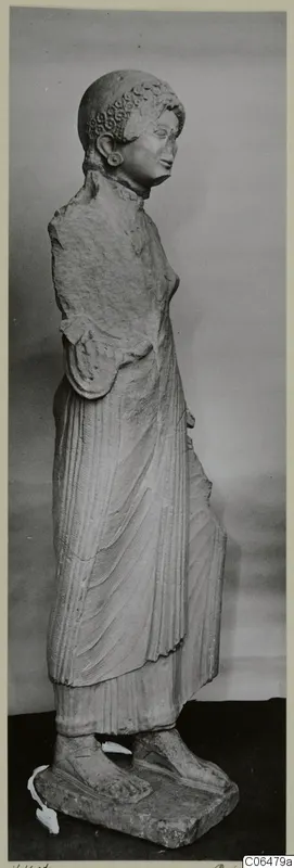 Limestone statue of a standing woman from Vouni, shown from the side on a rectangular base.