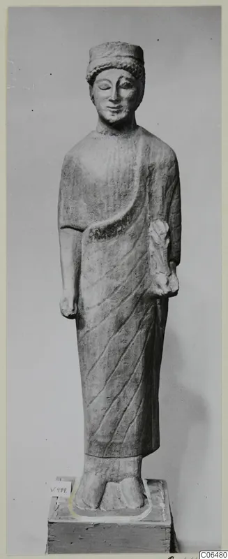 Limestone statue of a standing male figure in a cap and draped cloak, on a wooden base, from Vouni