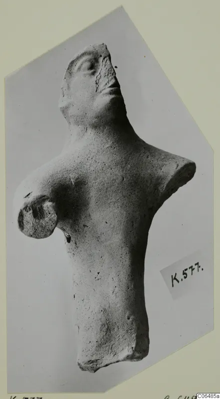 Terracotta figurine of a head and torso with one arm, photographed on a pale mount