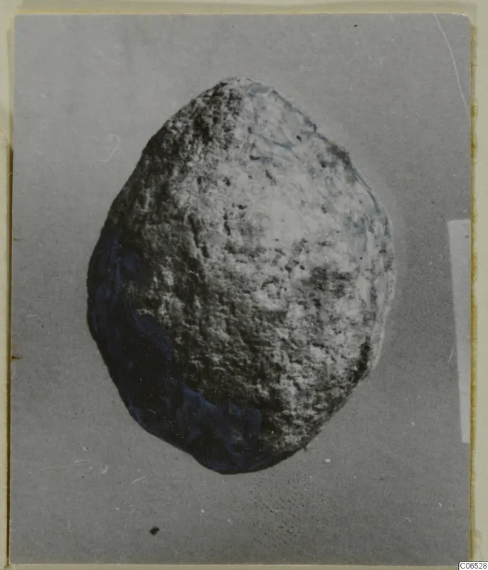 Rounded lump of lead with a pitted grey surface and blue-tinged patches, photographed on a plain grey background.
