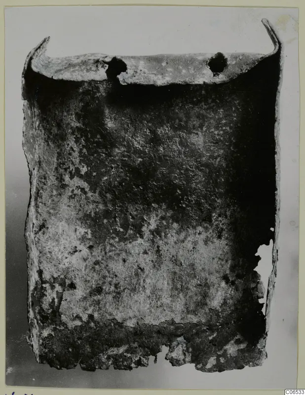 Corroded bronze shovel-like blade with a turned-up rim and two holes, from Vouni