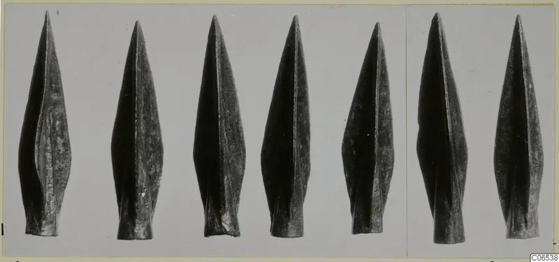 Bronze Age weapon points from Vouni, a row of pointed leaf-shaped blades photographed on a grey ground