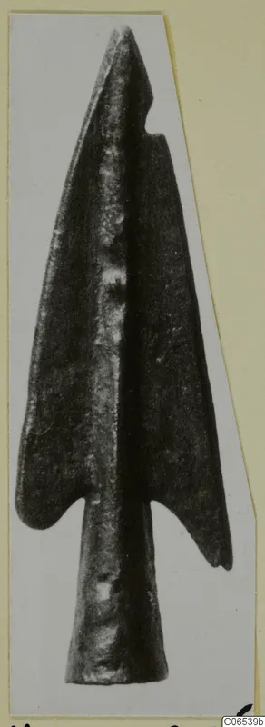 Bronze barbed point from Vouni, shown on a pale card mount