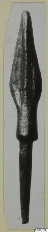 Bronze spearhead with a leaf-shaped blade and long tapering socket, shown upright on a pale card mount