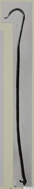 Bronze utensil handle from Vouni: a long thin rod with a hooked end, shown against a grey backdrop.