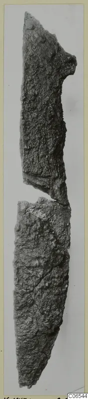Two broken pieces of a heavily corroded iron knife, shown upright against a grey background