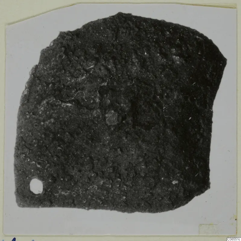 Corroded bronze mounting fragment with a small hole near the lower left corner