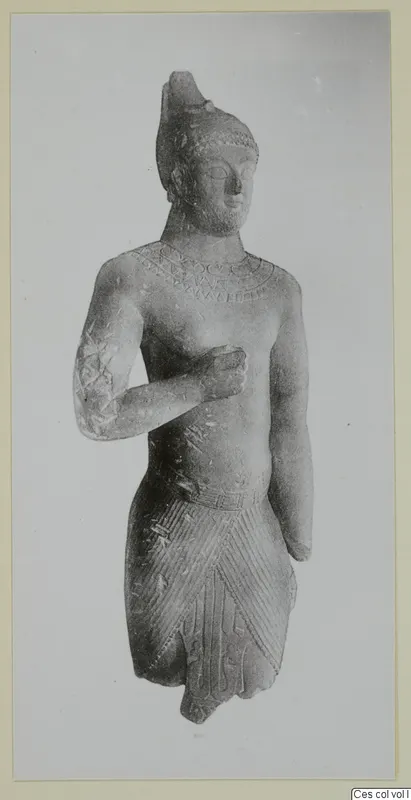 Limestone statue of a standing figure with a tall headdress, bent arm across the chest and incised drapery.