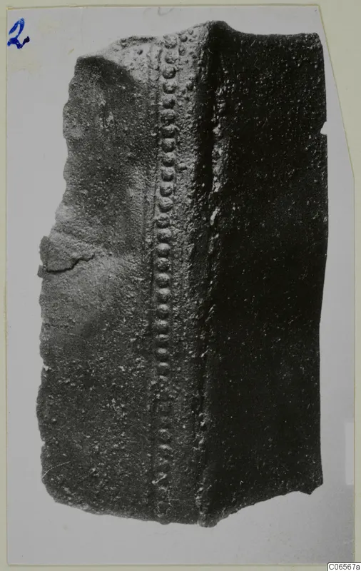 Corroded bronze fragment with a raised ridge of rounded studs running down one face