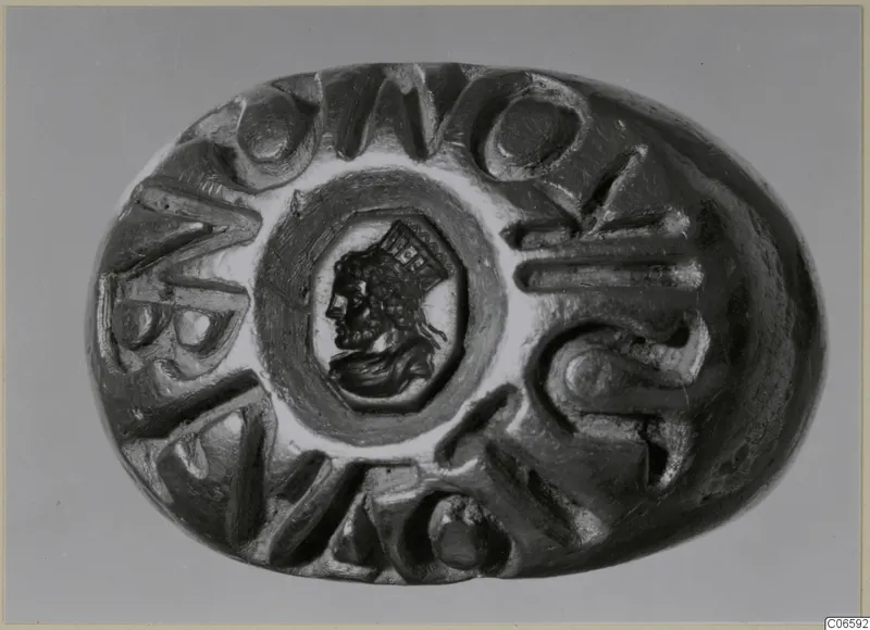 Oval seal or gem with a carved profile head in the centre, surrounded by raised letters around the edge