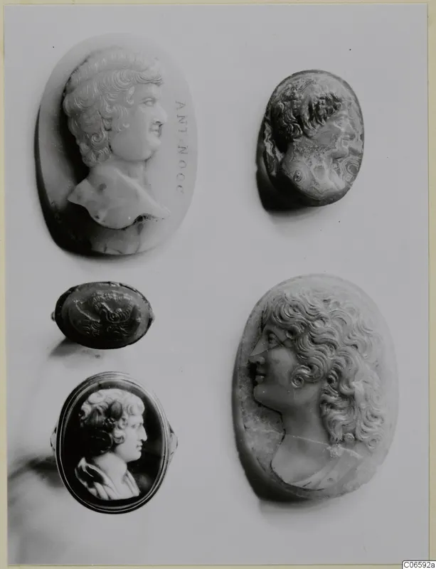Five carved gems and cameos on a pale mount, most showing male or female heads in profile.