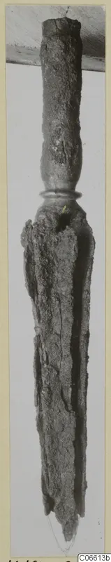 Corroded iron weapon butt-spike from Vouni, shown upright on a mounted card