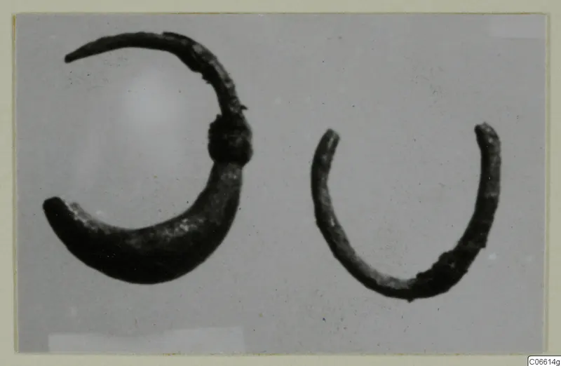 Two corroded silver hoops, one larger than the other, photographed on a plain grey background