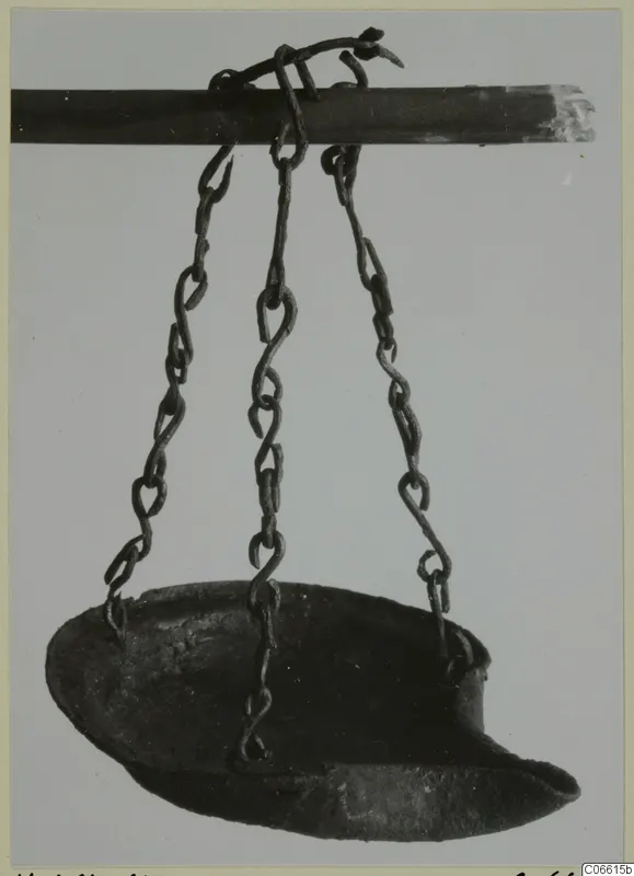 Metal lamp hanging by three chains from a horizontal rod