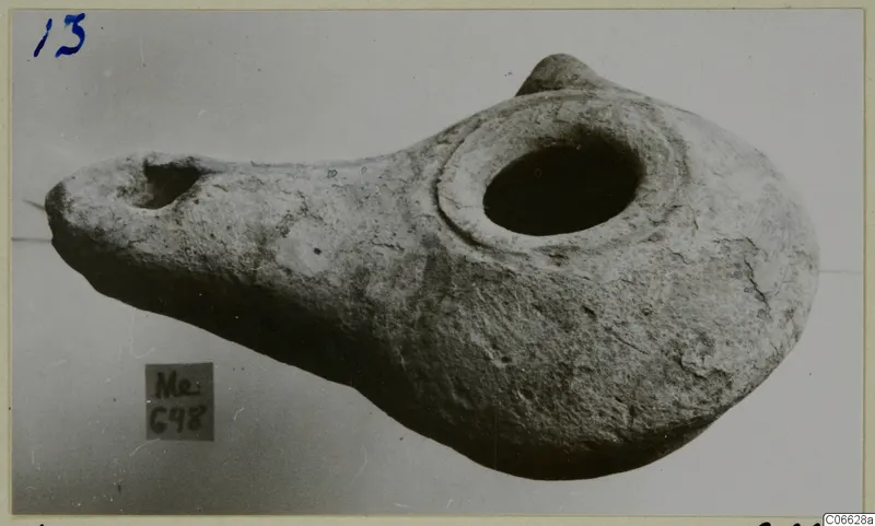 Terracotta oil lamp with a large central filling hole and a nozzle at the left end.