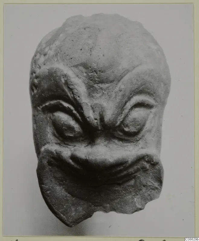 Small terracotta head from Mersinaki with heavy brow ridges, bulging eyes and a wide grimacing mouth