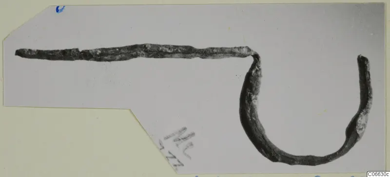 Fibula fragment of bronze from Mersinaki: a long thin pin bent into a curved loop at one end.