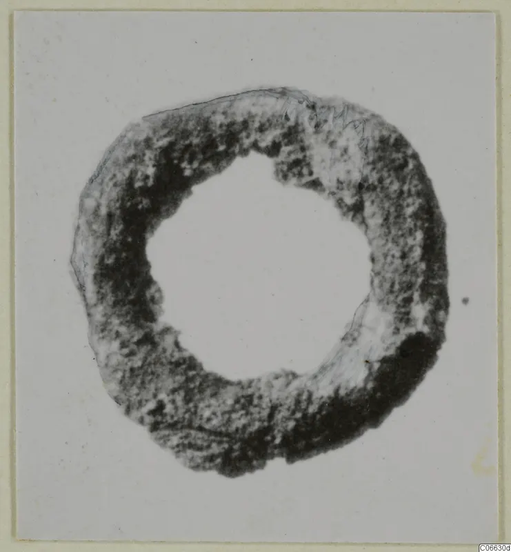 Ring-shaped bronze fragment from Mersinaki, seen face-on against a pale card background.