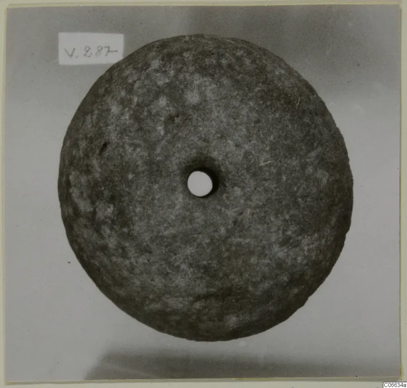 Stone loom weight from Vouni, a flat round disc with a central hole