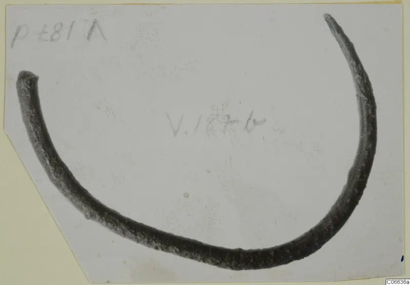 Open bronze bracelet, a single curved bar with tapering ends, mounted on a card with handwritten labels