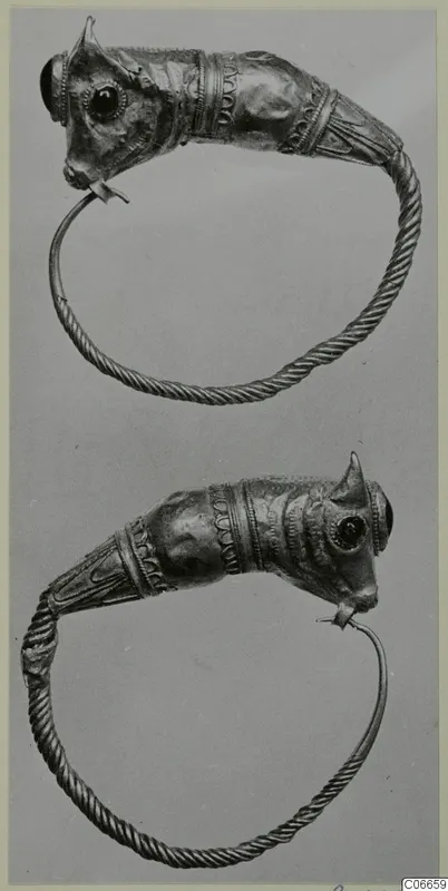 Two gold penannular rings with animal-head terminals, dark stone-set eyes and twisted wire bands