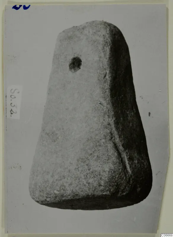 Trapezoidal worked object with a round hole near its top, from Soli