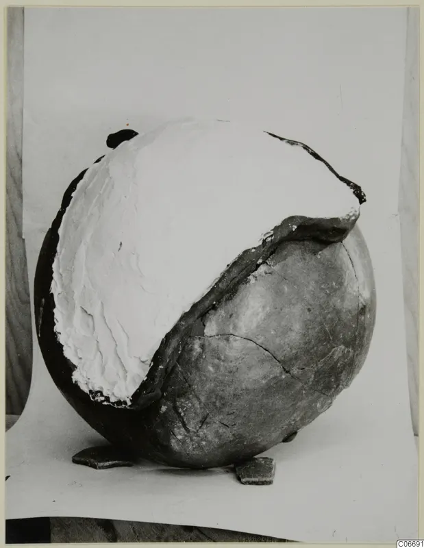 Pottery jug with a large white filler covering its upper part, with two loose sherds at its base