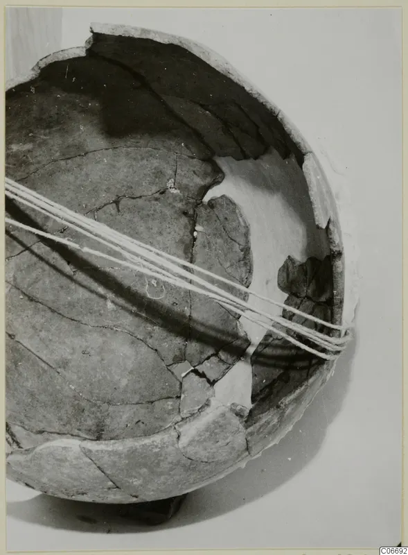 Reconstructed Red Polished II jug, made of broken sherds bound together with white cord, shown against a pale background.